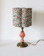 Abat-jour beige fleuri sur pied de lampe laiton avec base orange.