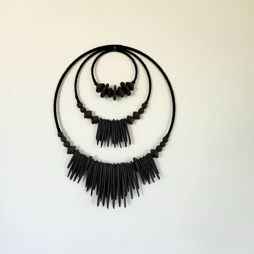 Décoration murale XXL noire en perles et franges, vue complète sur fond clair
