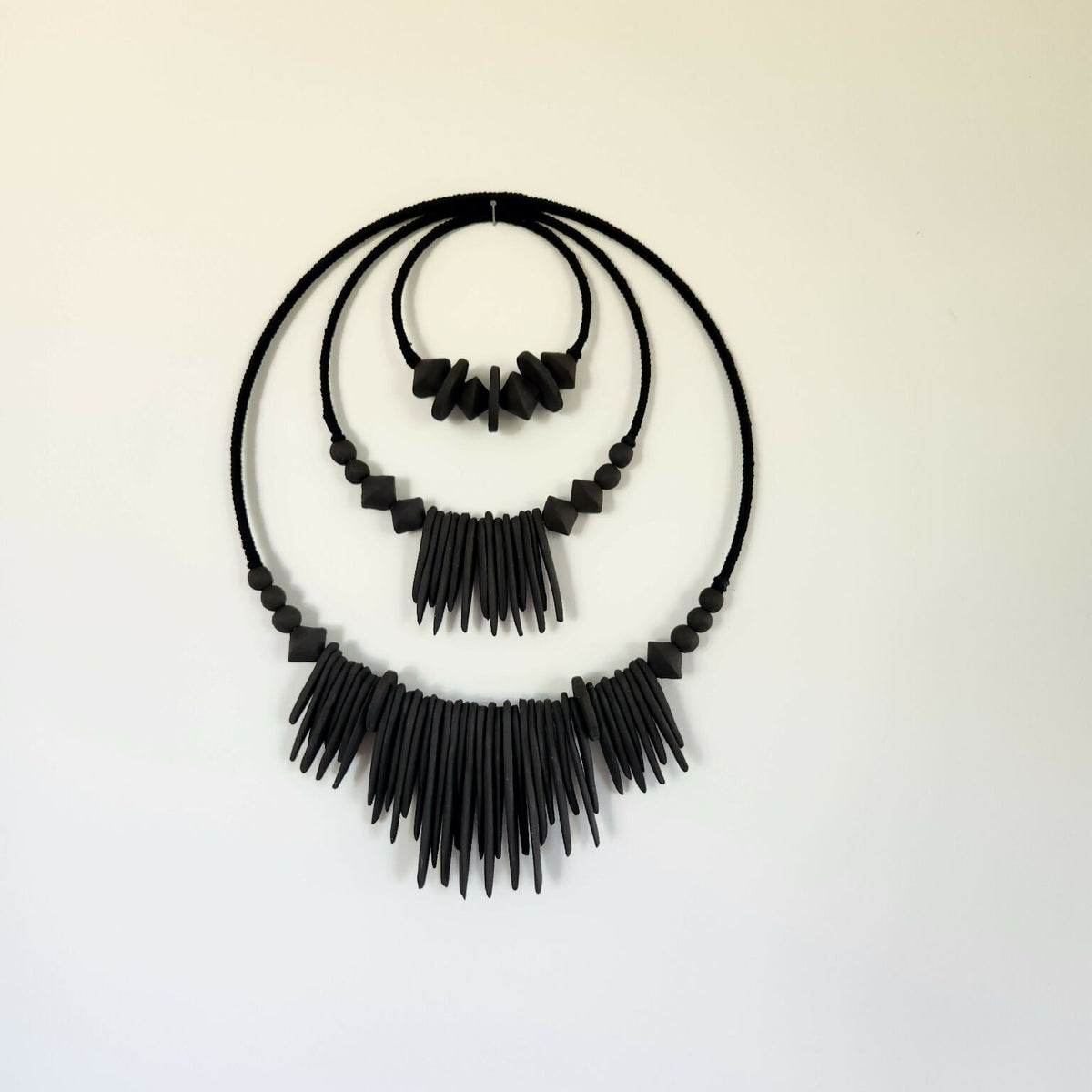Décoration murale XXL noire en perles et franges, vue complète sur fond clair