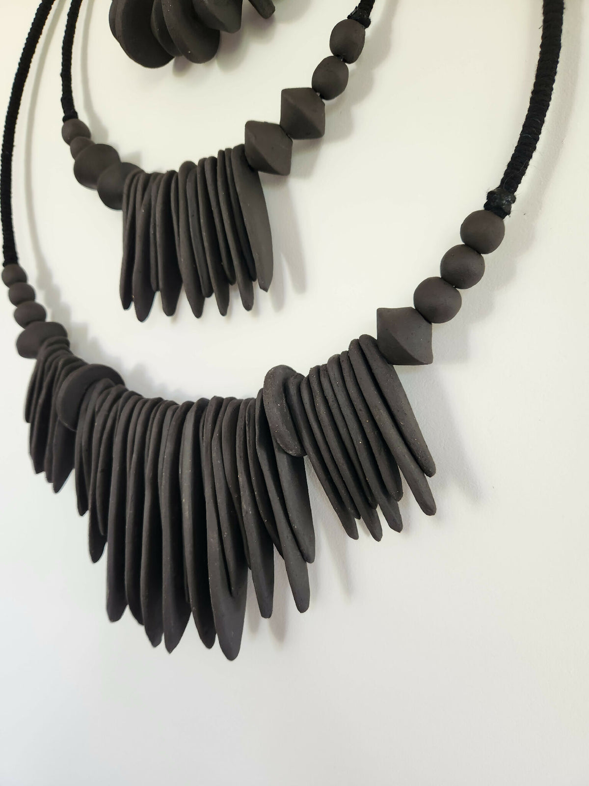 Décoration murale XXL noire en perles et franges, gros plan sur les motifs en U