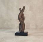 Sculpture contemporaine en métal patiné, forme de flamme abstraite sur socle noir.