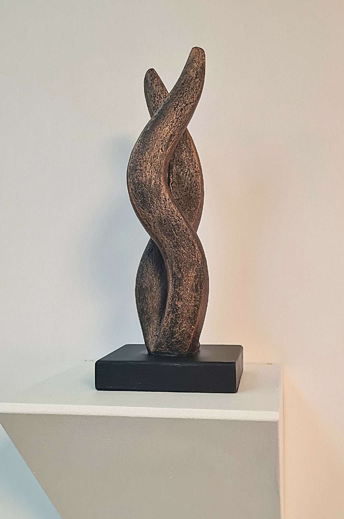 Sculpture contemporaine bronze en forme de flamme, posée sur socle noir