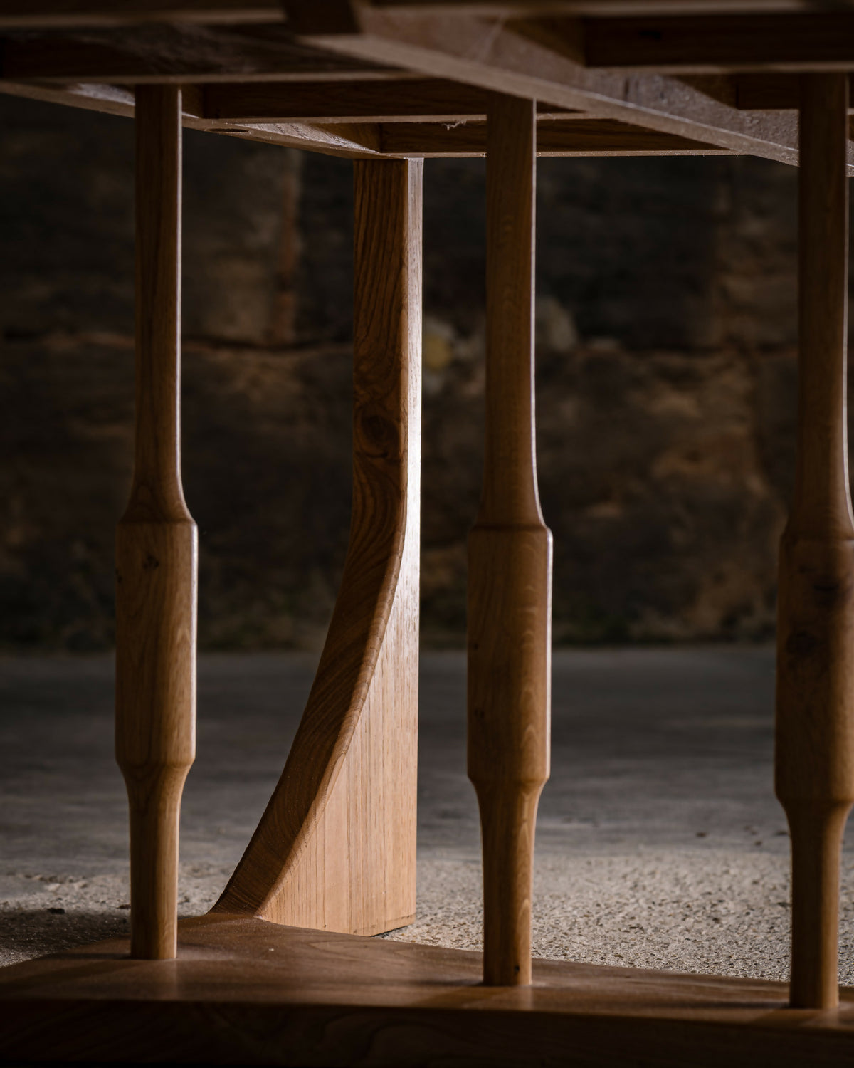 Table basse en bois clair : détail du piétement tourné et de la base sous le plateau