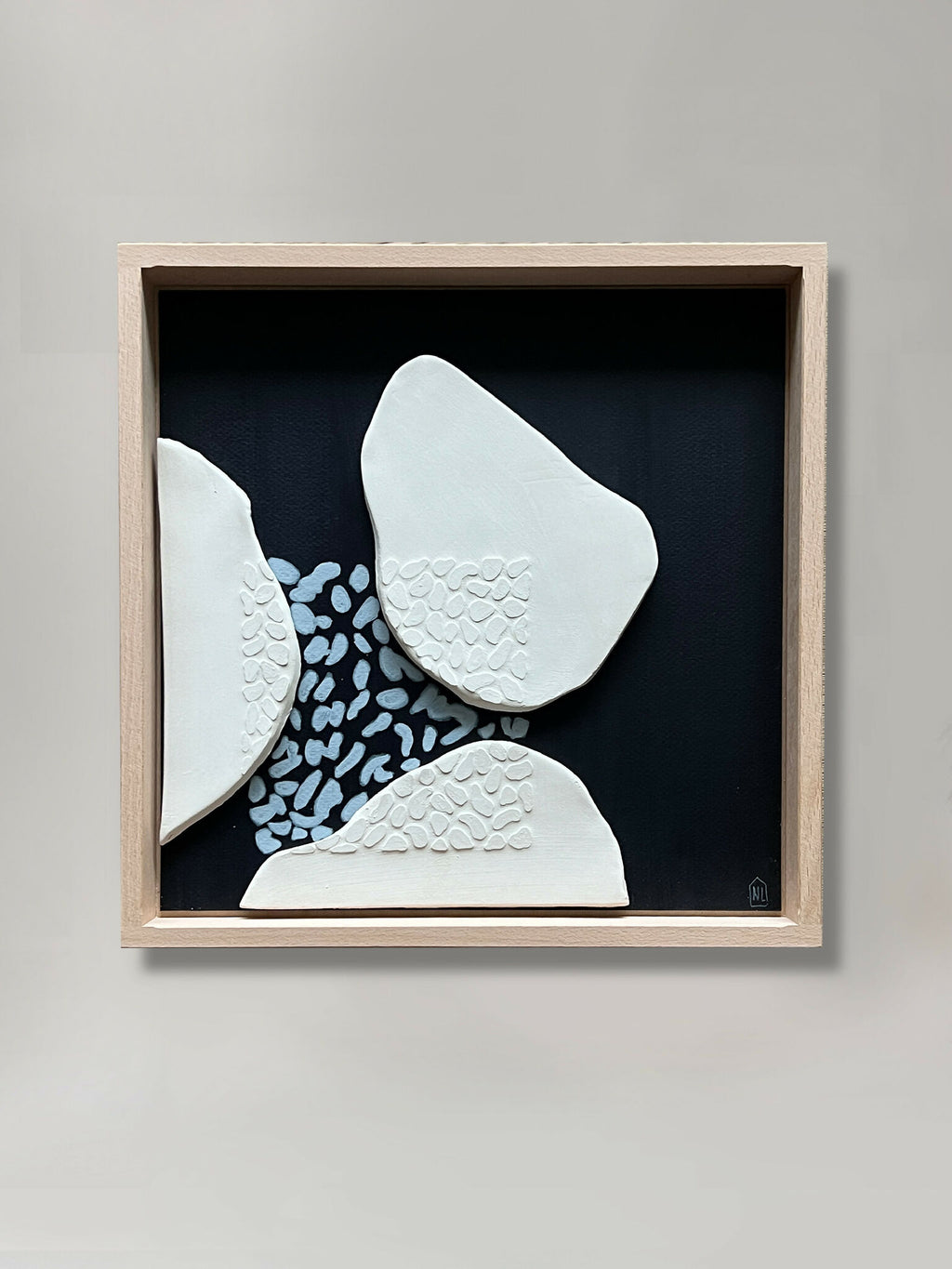 Tableau en relief avec formes blanches sur fond bleu foncé, cadre en bois clair