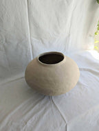 Vase en céramique beige, petit col évasé et intérieur sombre.