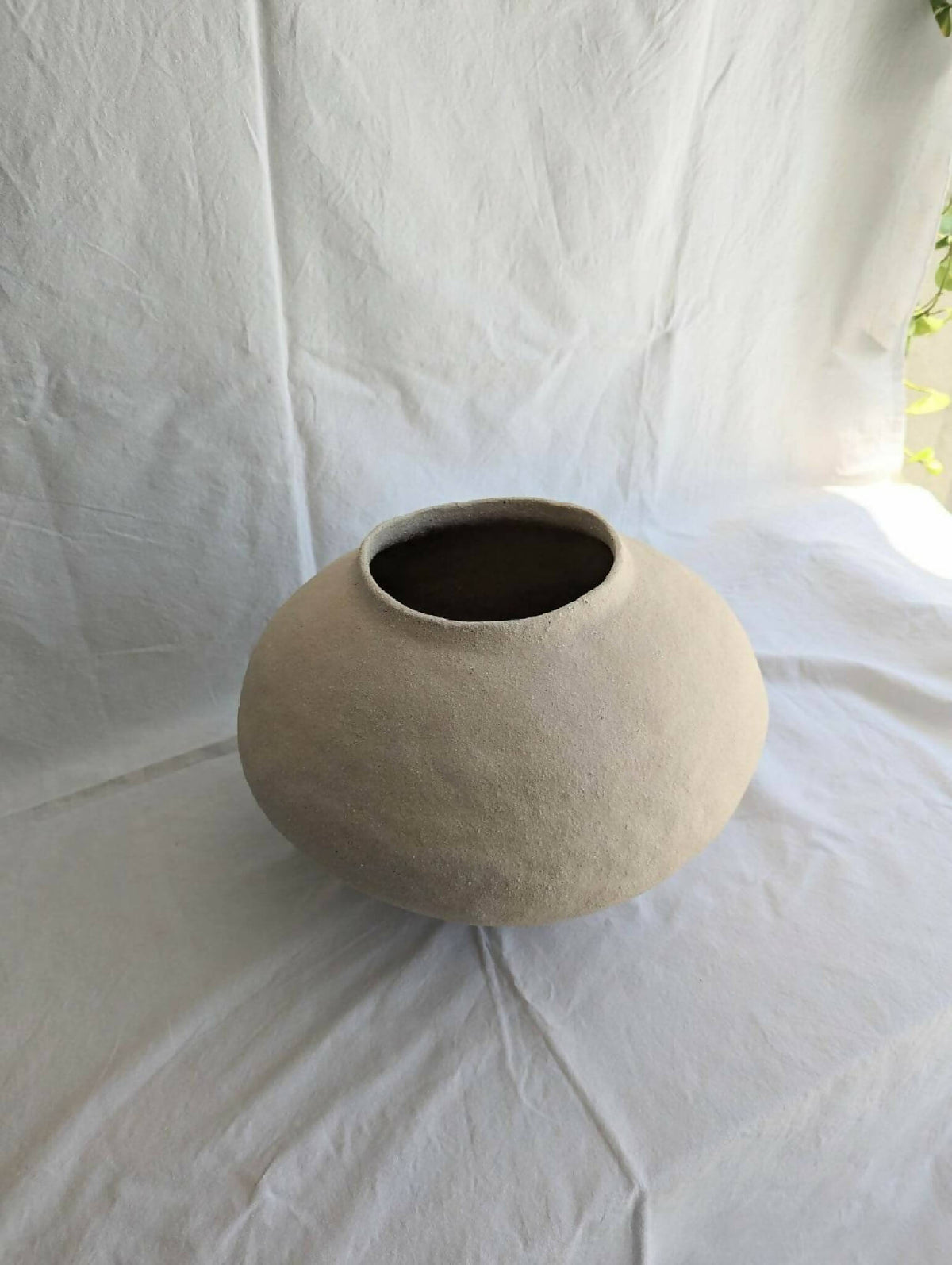 Vase en céramique beige, petit col évasé et intérieur sombre.