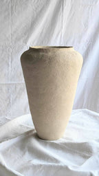 Vase en céramique beige à forme conique, ouverture large au bord sombre.