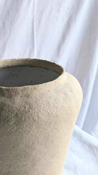 Ouverture du vase conique en céramique beige, bord supérieur foncé.
