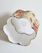 Abat-jour forme fleur avec ouverture blanche, bord festonné, motif floral rouge et bleu.