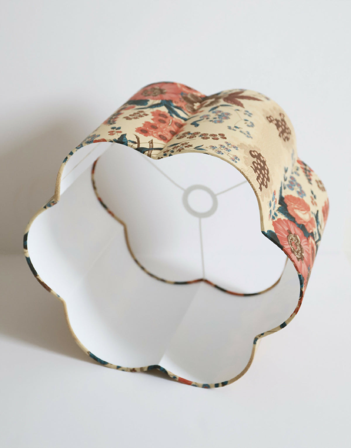 Abat-jour forme fleur avec ouverture blanche, bord festonné, motif floral rouge et bleu.