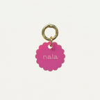 Médaille Bloom en émail rose, anneau doré, texte « nala » au centre.