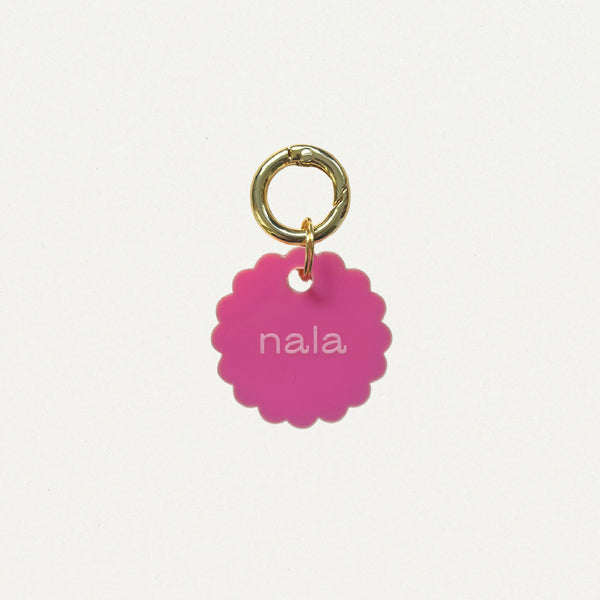 Médaille Bloom en émail rose, anneau doré, texte « nala » au centre.