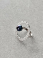Bague argentée texturée en forme d’anneau ovale, cabochon bleu foncé visible de côté