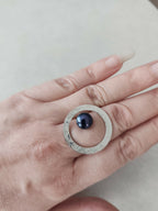 Bague ovale argentée texturée sur la main, cabochon bleu foncé au centre