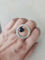 Bague argentée texturée ovale portée, cabochon bleu foncé et anneau visible