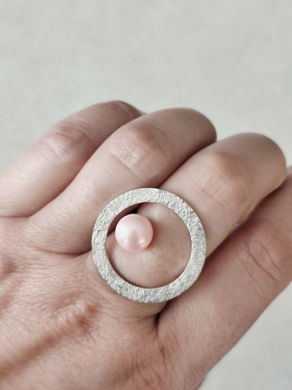 Bague Atoll portée : perle rose nacrée sur monture argentée texturée