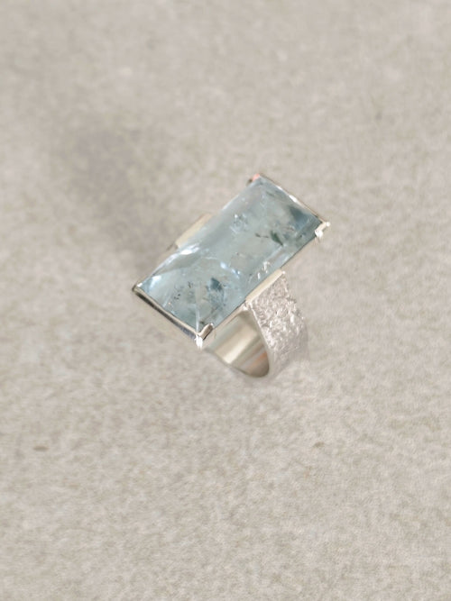 Bague en topaze bleu clair rectangulaire, monture argent, vue de profil.