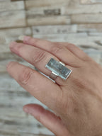 Bague en topaze bleu clair rectangulaire sur paume, anneau argent, vue en plongée.