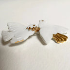 Broche colombes blanches, motif doré au centre et épingle arrière visible.