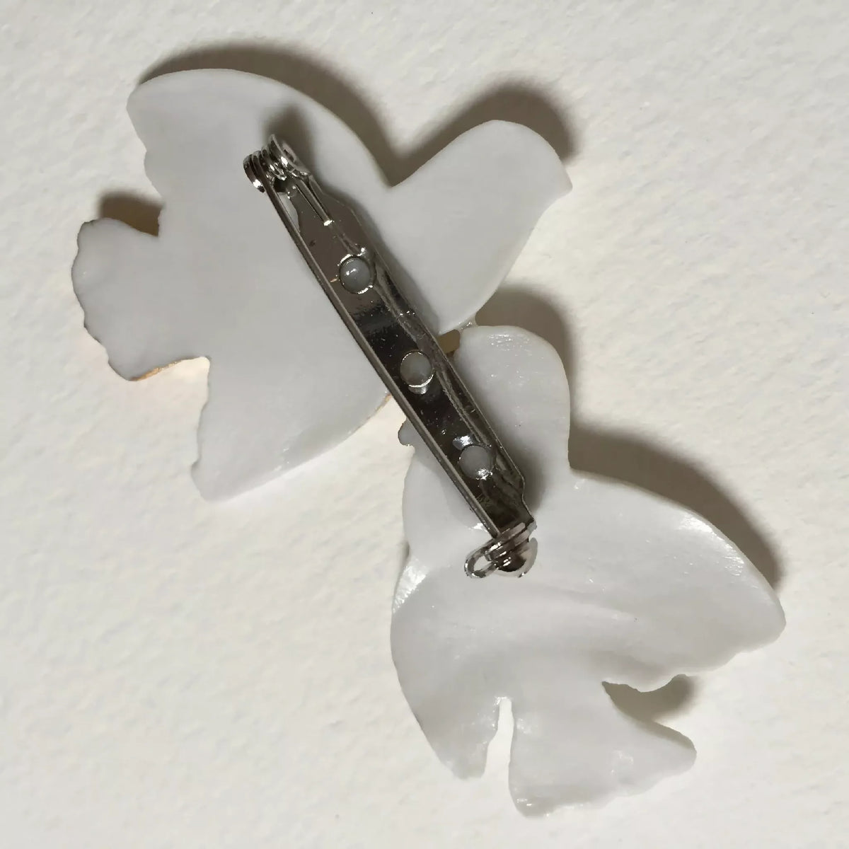 Broche colombes blanche avec épingle et fermoir métallique au dos.