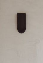 Applique murale en céramique marron, vue rapprochée, éclairage intégré vers le bas.