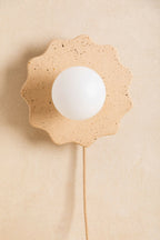 Applique murale en forme de fleur beige clair, globe blanc et câble beige.