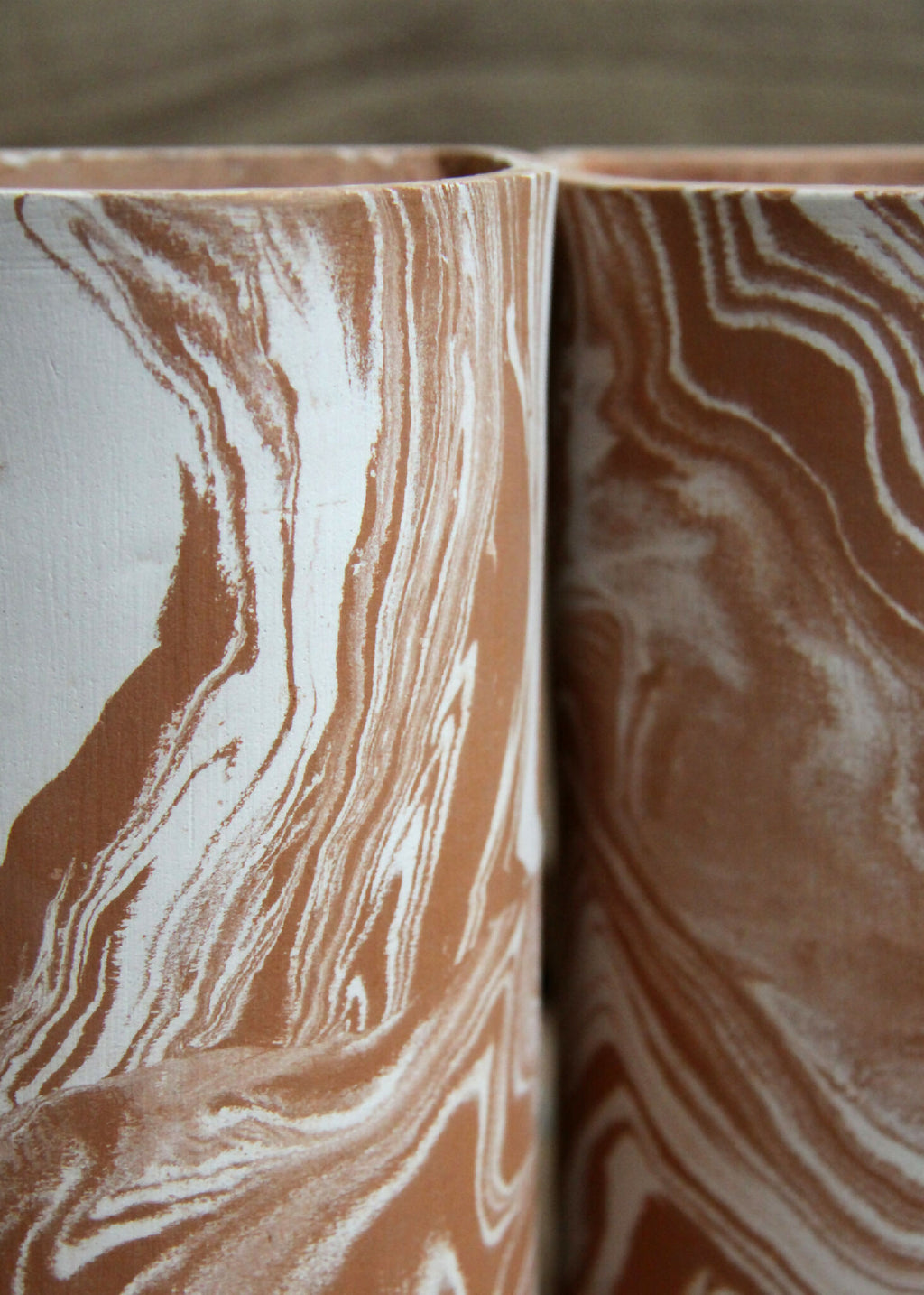Deux gobelets cylindriques en céramique marbrée beige et brun, vue rapprochée