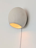 Applique en céramique ronde grise, lumière orange, sur un câble torsadé blanc