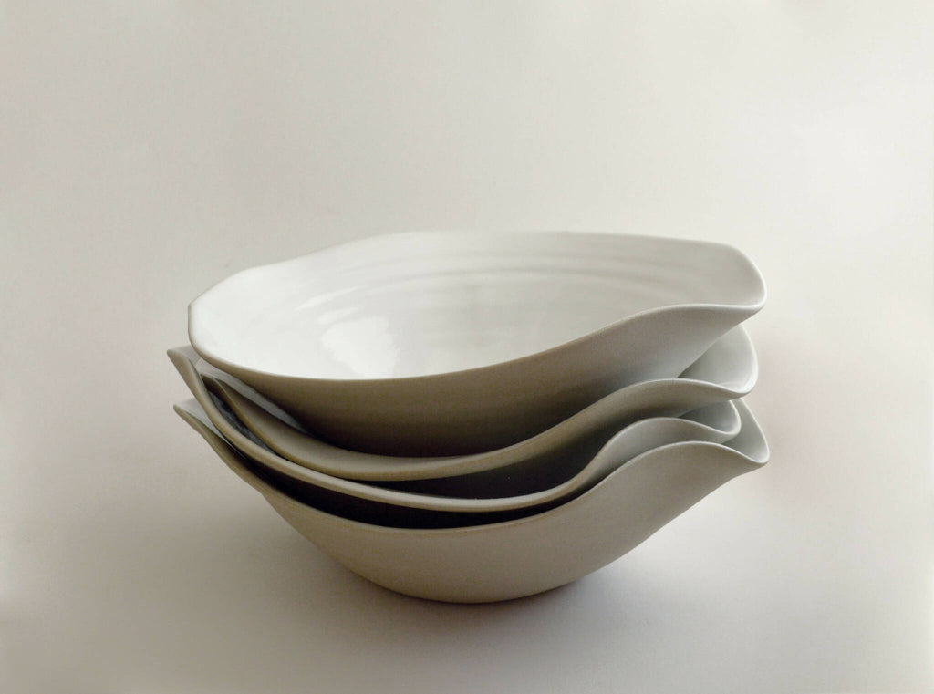Lot d’assiettes creuses en céramique blanche empilées, bord ondulé