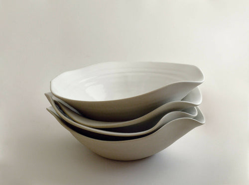 Lot d’assiettes creuses en céramique blanche empilées, bord ondulé
