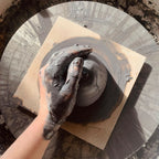 Mug en céramique en cours de finition, intérieur peint avec une main gantée