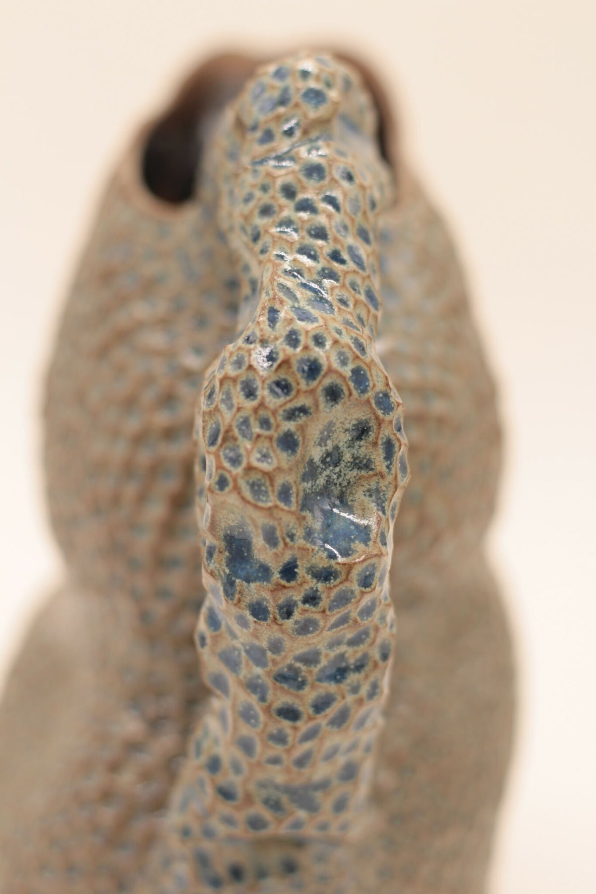 Pichet en céramique bleu moucheté, gros plan du bec et du motif granuleux.