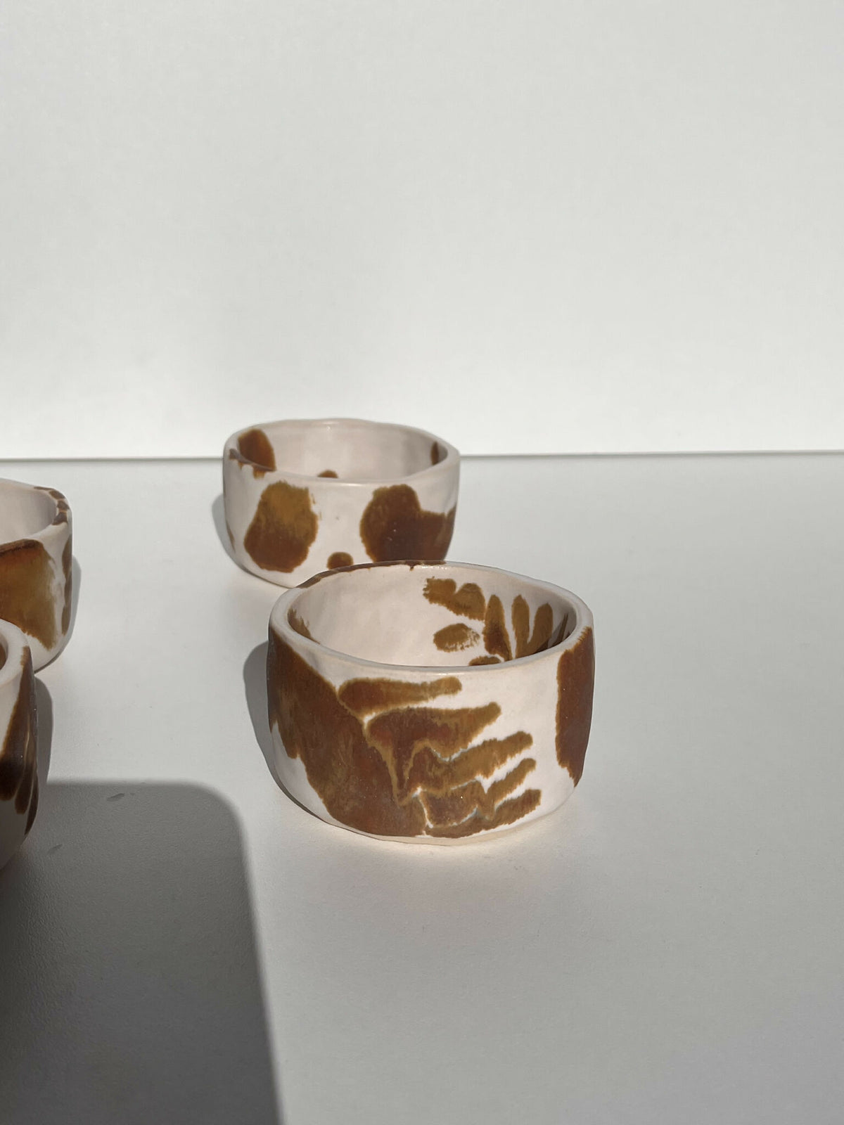 Tasses en céramique blanches à motifs abstraits marron, vue de deux modèles empilés