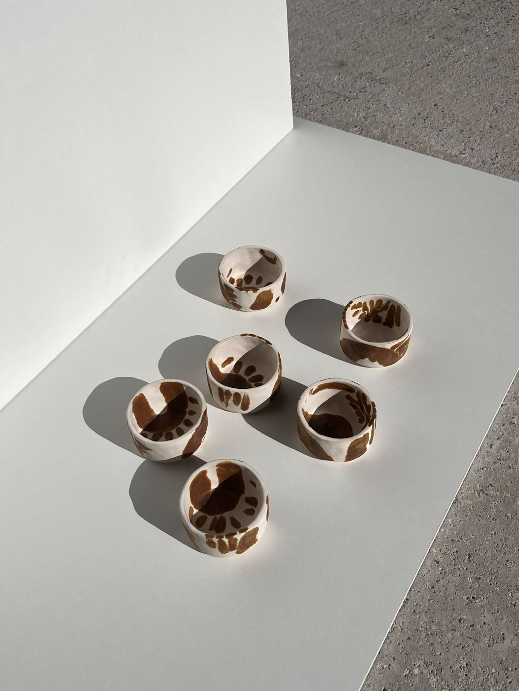 Petit lot de tasses en céramique blanches à motifs abstraits marron, vue de dessus