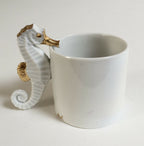 Tasse blanche avec hippocampe décoratif doré sur la poignée