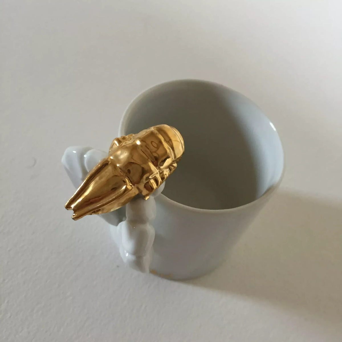 Tasse blanche avec homard doré sur l’anse, vue de côté