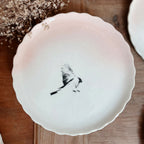 Assiette à dessert en porcelaine blanche, bord festonné, oiseau noir avec ailes déployées
