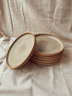 Assiettes creuses en céramique beige à bord brun, pile avec une assiette soulevée