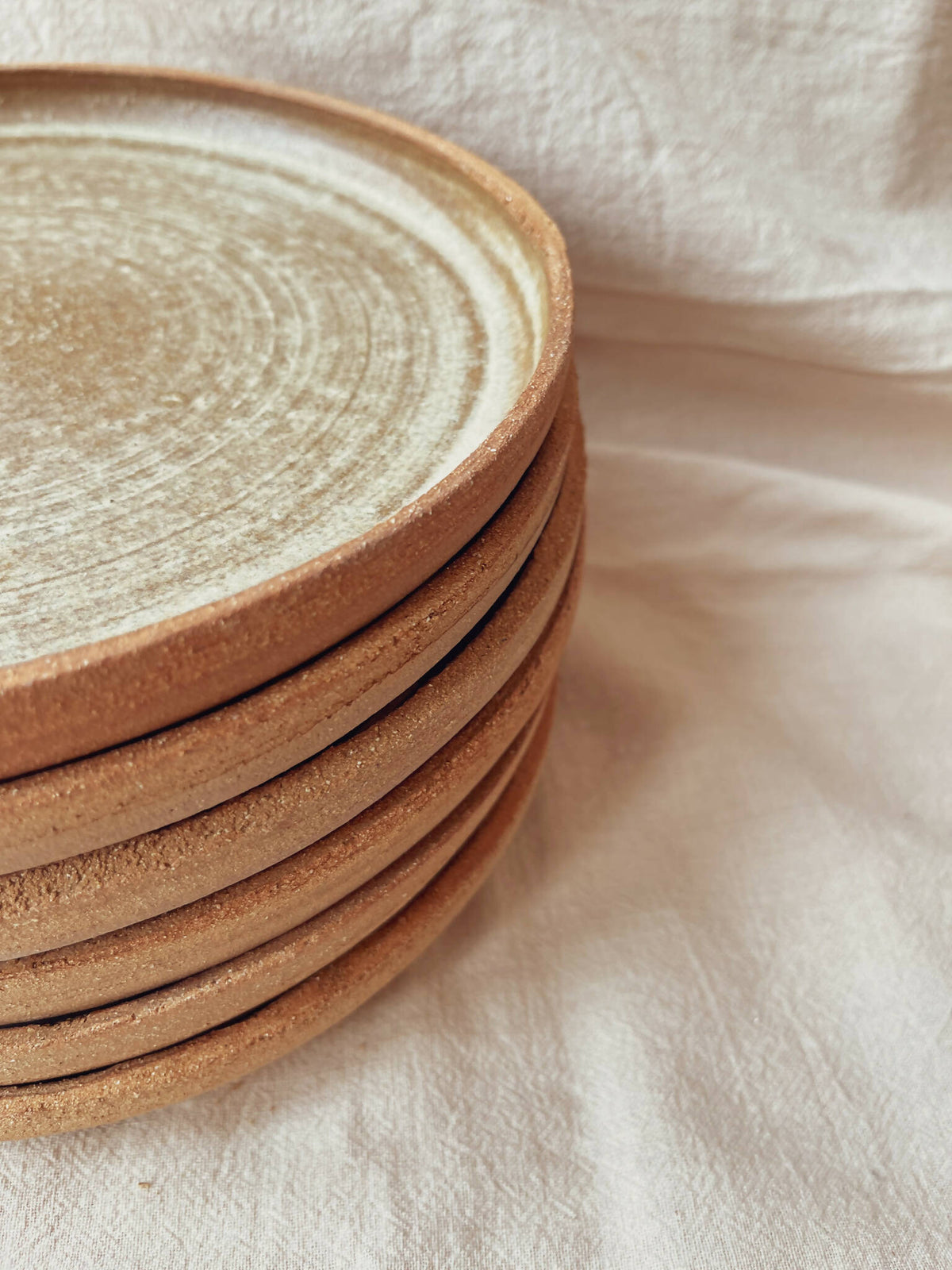 Assiettes creuses en céramique beige à bord brun, gros plan sur pile superposée