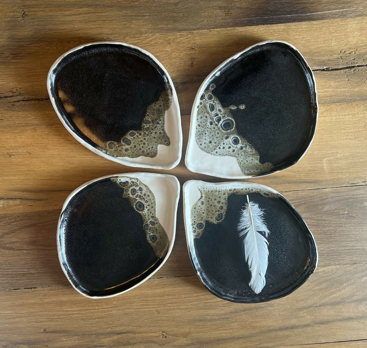 Jeu de 4 petites assiettes BT ovales noir, bord blanc, motifs et une plume