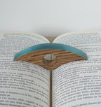 Marque-page en bois bleu turquoise sur livre ouvert, motif ajouré