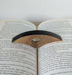 Accessoire de lecture sur livre ouvert, bande noire et marqueterie brunâtre, ouverture ovale.