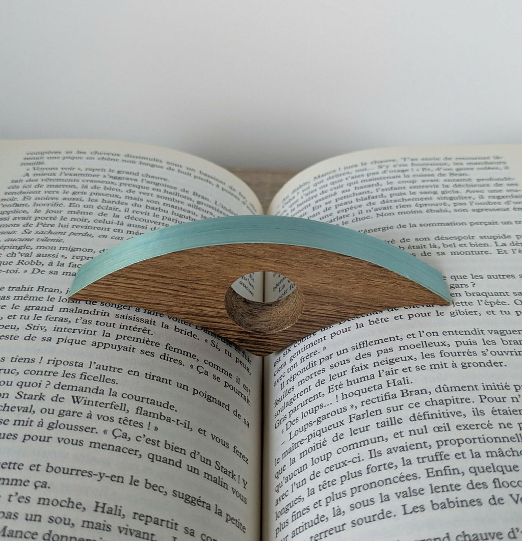 Bague de lecture en bois turquoise, sur les pages d’un livre imprimé
