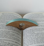Bague de lecture en bois turquoise, sur les pages d’un livre imprimé