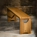 Banc en bois clair avec plateau rectangulaire et ouverture demi-lune sur le piètement.