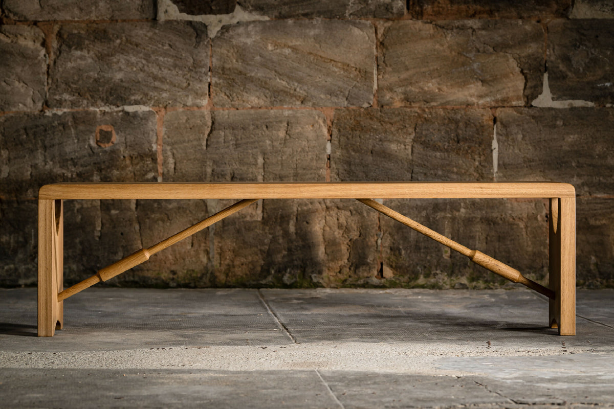 Banc en bois clair avec cadre inférieur en bois et renforts inclinés.