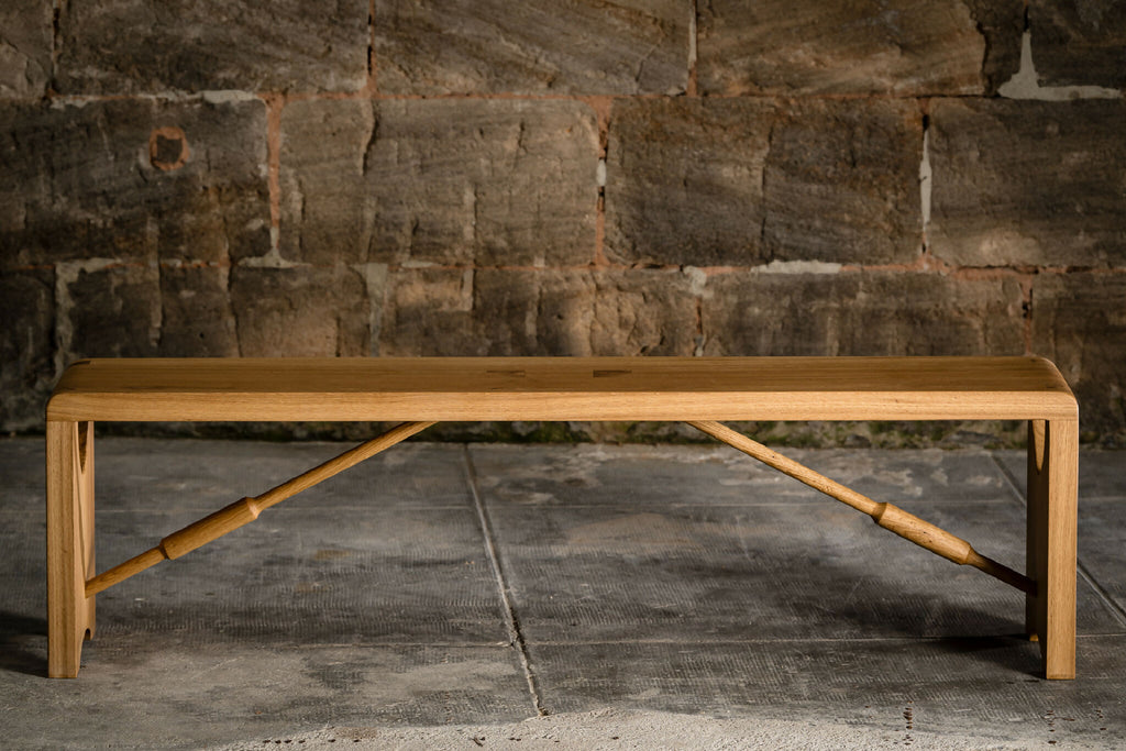Banc en bois clair vu de dessous : renforts en bois en X sous le plateau.