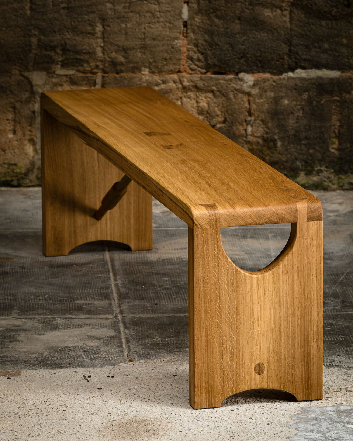 Banc en bois clair avec plateau incliné, ouverture demi-lune et piètement en U.