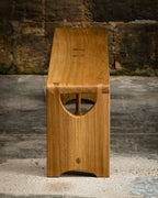 Banc en bois clair avec poignée ajourée en forme de demi-lune sur le côté.