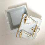 Boîte à bijoux en porcelaine blanche, couvercle avec motif balance doré, vue en biais.